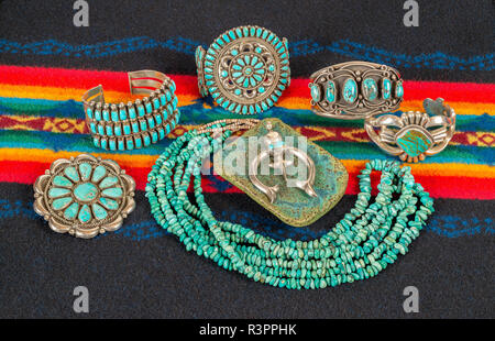 Collezione di gioielleria dei Nativi americani su un colorato sfondo tessili. Il turchese e Sterling Silver Necklace, Bracciali Ciondoli e. Foto Stock
