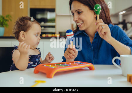 Felice il bambino e la madre figlia gioca con sonagli Foto Stock