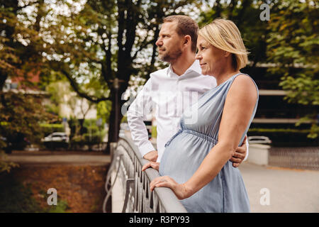 Coppia incinta giovane permanente al ponte in posizione di parcheggio Foto Stock