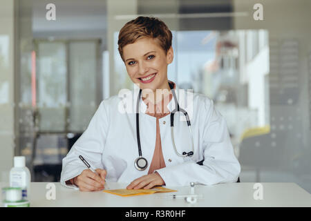 Ritratto di un fiducioso medico donna, riempimento nella scheda di immunizzazione Foto Stock