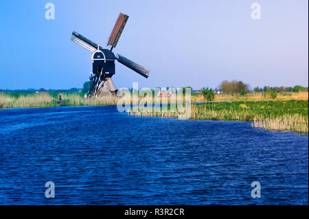 Tipico paesaggio dei polder olandesi con un tradizionale mulino a vento contro il cielo blu. Foto Stock