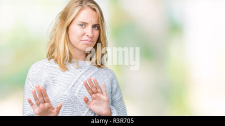 Giovane e bella donna che indossa un maglione invernale su sfondo isolato disgustato espressione, orinato e timorosi facendo il disgusto di fronte perché avversione Foto Stock