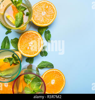 Cibo sano, estate limonata fresca con le arance, i limoni e le foglie di menta in bicchieri di vetro, vista dall'alto luogo di confine per il testo su sfondo blu Foto Stock