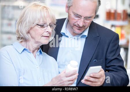 Coppia senior medicina di controllo sul telefono cellulare in farmacia. Foto Stock