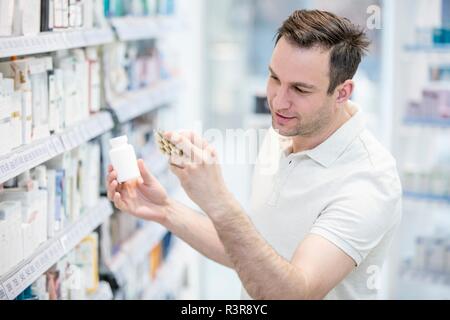 Cliente maschio lettura etichetta sulla pillola blister in farmacia. Foto Stock