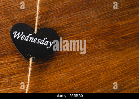 Cuore di legno nero con il giorno della settimana scritto su di esso, mercoledì Foto Stock