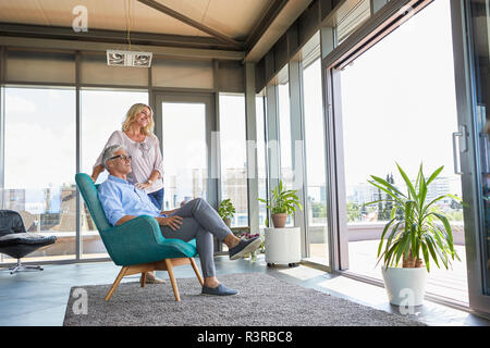 Coppia matura in un momento di relax a casa guardando fuori della finestra Foto Stock