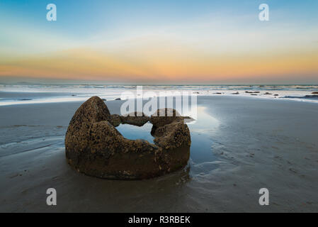 Nuova Zelanda, costa Otago, Moeraki Boulders Koekohe sulla spiaggia con cielo a sunrise Foto Stock