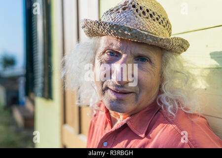 Ritratto di uomo anziano con lunghi capelli grigi che indossa cappello di paglia Foto Stock