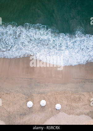 Indonesia, Bali, veduta aerea della spiaggia di Jimbaran, ombrelloni bianchi dal di sopra Foto Stock
