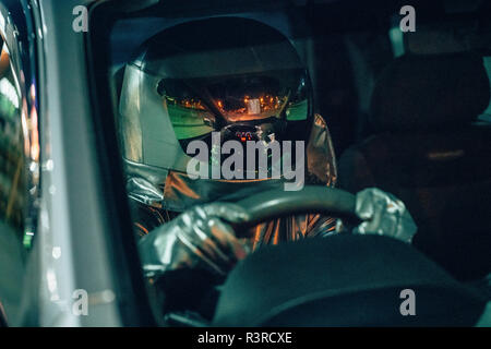 Spaceman guida auto di notte Foto Stock