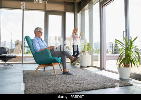 Coppia matura in un momento di relax a casa utilizzando tablet e telefono cellulare Foto Stock