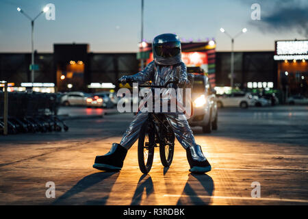 Spaceman nella città di notte sul parcheggio con la bmx bike Foto Stock