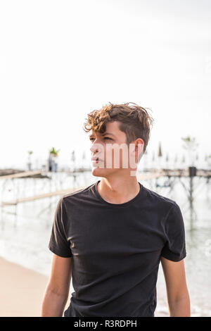 Ritratto di giovane uomo sulla spiaggia per guardare qualcosa Foto Stock