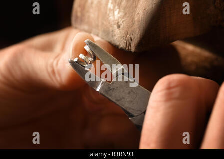 Goldsmith mani lavorando su un filo d'argento a spirale pinze con piccoli anelli di catena, macro shot con spazio di copia selezionato, focus, molto stretta la profondità di campo Foto Stock