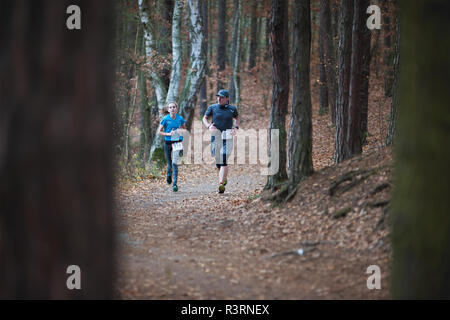 Repubblica ceca, Pilsen, Novembre 2018: Hannah Pilsen Krkavec Trail. Guide di scorrimento l uomo e la donna in esecuzione il passo nella foresta autunnale. Foto Stock