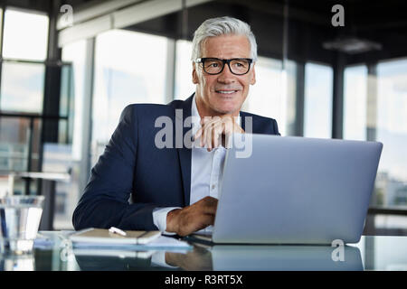 Imprenditore lavora in ufficio, con il computer portatile Foto Stock