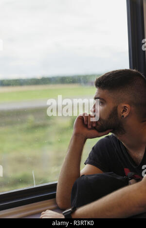Uomo che viaggia in treno guardando fuori della finestra Foto Stock