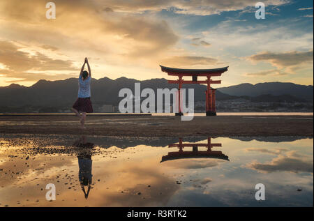 Donna godendo il tramonto sull'isola di Itsukushima o Miyajima, Hiroshima, Giappone Foto Stock