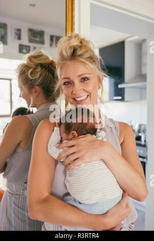 Ritratto di madre felice tiene il suo bambino vicino nella parte anteriore dello specchio a casa Foto Stock