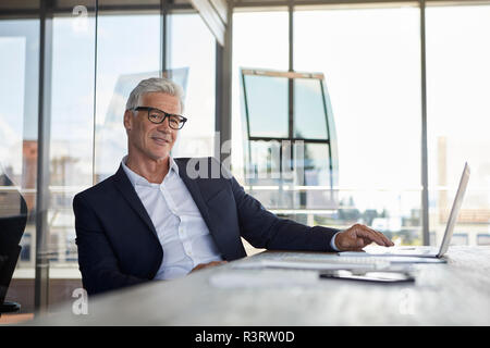 Imprenditore lavora in ufficio, con il computer portatile Foto Stock