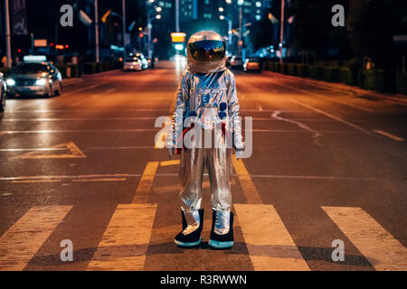 Spaceman in piedi su una strada della città di notte Foto Stock