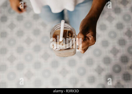 Mano di donna tenendo un bicchiere di caffè ghiacciato mi Foto Stock