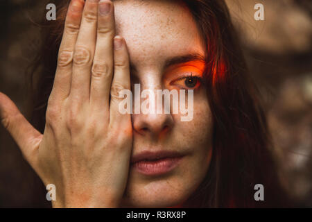 Ritratto di giovane donna con lentiggini che copre un occhio Foto Stock