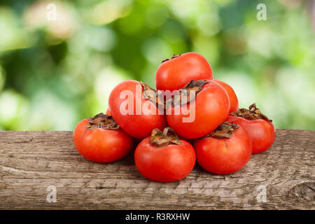 Persimmon frutta sul tavolo in legno con giardino sfocata sullo sfondo Foto Stock