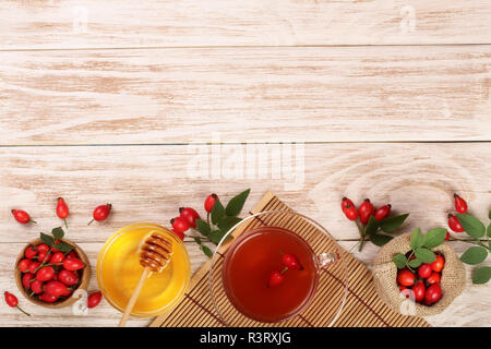 Tè con rosa canina e miele bianco su sfondo di legno con una copia dello spazio per il tuo testo. Vista superiore Foto Stock