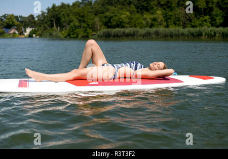 La Germania, il Land Brandeburgo, giovane donna relax su paddleboard su Zeuthener vedere Foto Stock