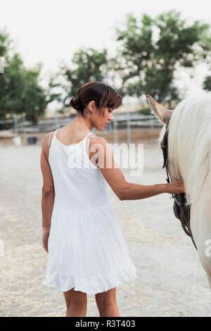 Vista posteriore della donna in abito bianco cavallo leader Foto Stock