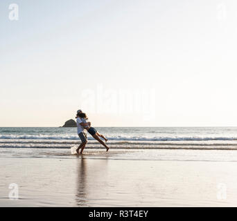 Coppia giovane abbracciando sulla spiaggia Foto Stock
