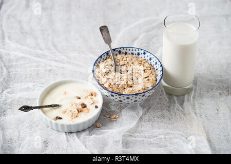 Bocce di granola, fiocchi di avena e yogurt naturale e un bicchiere di latte Foto Stock