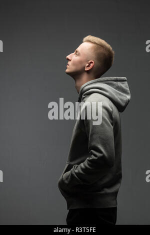 Profilo del biondo giovane uomo grigio da indossare giacca con cappuccio Foto Stock