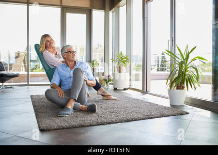 Coppia matura in un momento di relax a casa guardando fuori della finestra Foto Stock