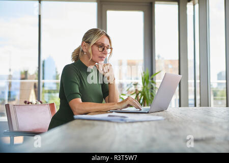 Donna matura utilizzando computer portatile sul tavolo a casa Foto Stock