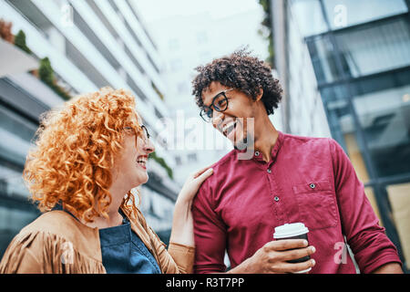 I colleghi camminare insieme nella città, donna di bere il caffè Foto Stock