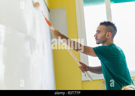 L'uomo pittura parete in corrispondenza di nuovo home Foto Stock