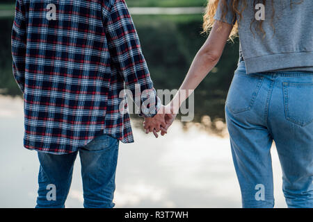 Coppia romantica permanente al Riverside, tenendo le mani Foto Stock