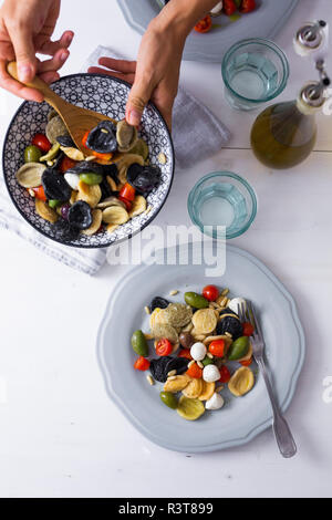 Donna cucina mediterranea orecchiette con pomodoro, olive e mozzarella Foto Stock