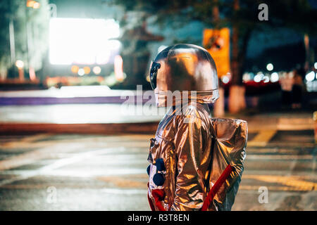 Spaceman su una strada della città di notte attratti dalla brillante schermo di proiezione Foto Stock