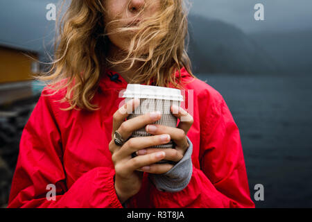 Norvegia, Lofoten, close-up di giovane donna presso la costa azienda caffè da asporto Foto Stock