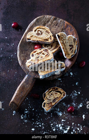 Tagliate a fette il Natale lo Stollen con dello zucchero a velo su una paletta di legno Foto Stock