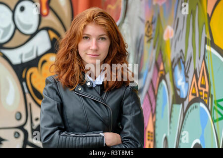 L'Italia, Finale Ligure, ritratto di redheaded ragazza vestita di nero giacca di pelle nella parte anteriore del murale Foto Stock