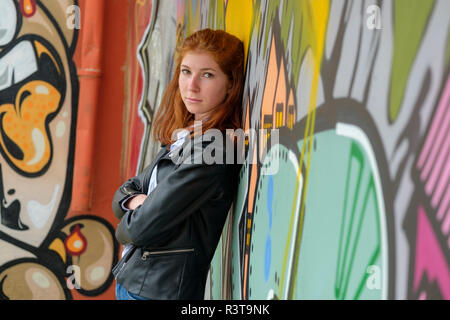 L'Italia, Finale Ligure, ritratto di redheaded ragazza adolescente appoggiata contro il murale Foto Stock