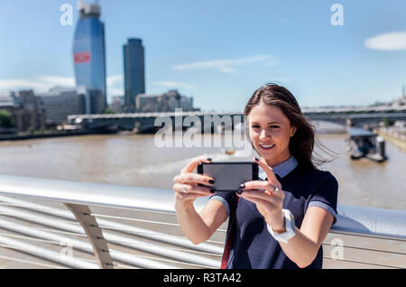 UK, Londra, donna prendendo un selfie sul Millennium Bridge Foto Stock