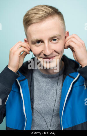 Ritratto di giovane sorridente uomo a mettere su auricolari Foto Stock