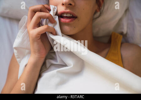 Aprire la bocca di una giovane donna giaceva a letto Foto Stock