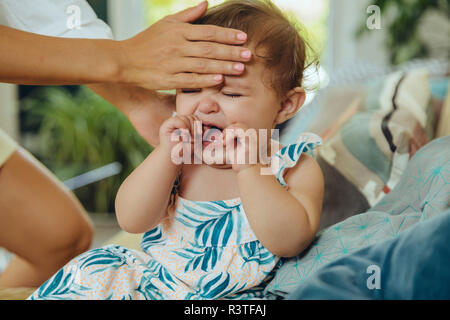 Madre tenendo la temperatura del suo pianto Baby girl Foto Stock